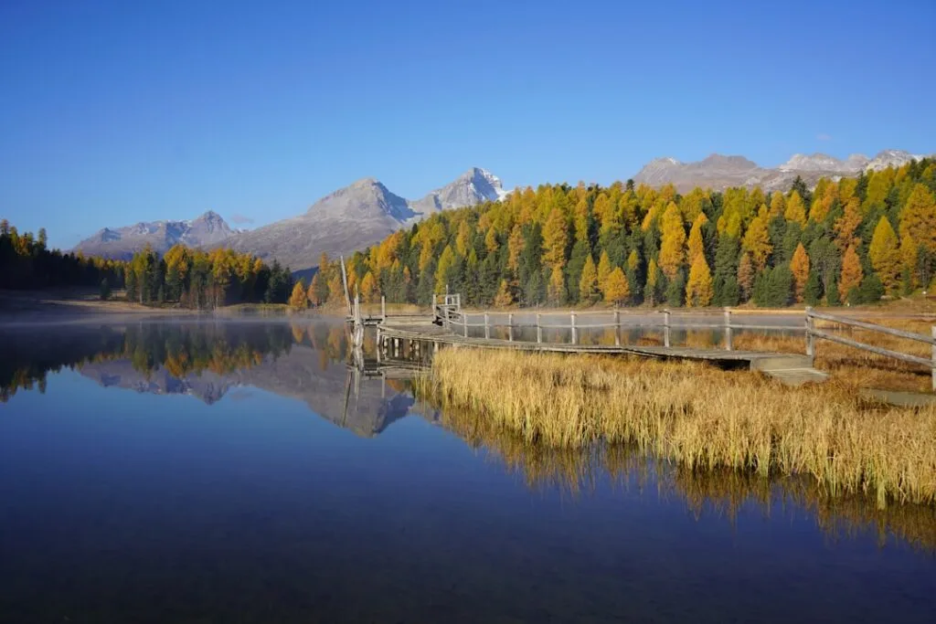 Ponton en bois reflété sur un lac alpin calme, Dolomites