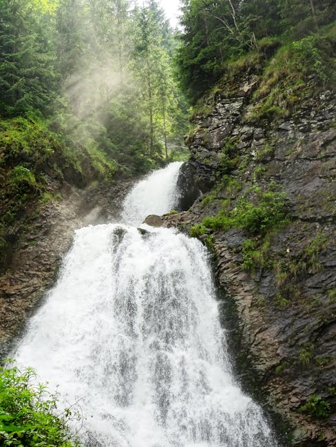 Wasserfall stürzt zwischen Felsen und Tannen, Nebel über den Dolomiten