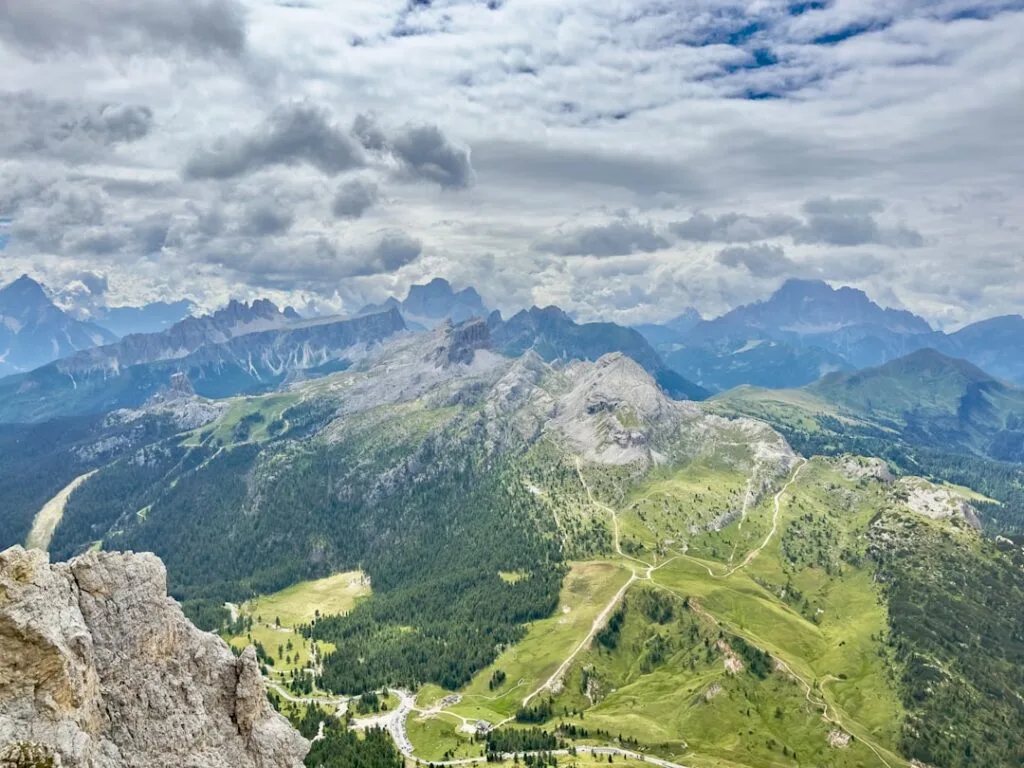 Uitzicht over groene Dolomietenweiden met kronkelende wandelpaden en wolken