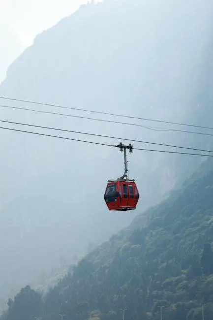 Rode gondelbaan hangend boven een mistig dal in de Dolomieten