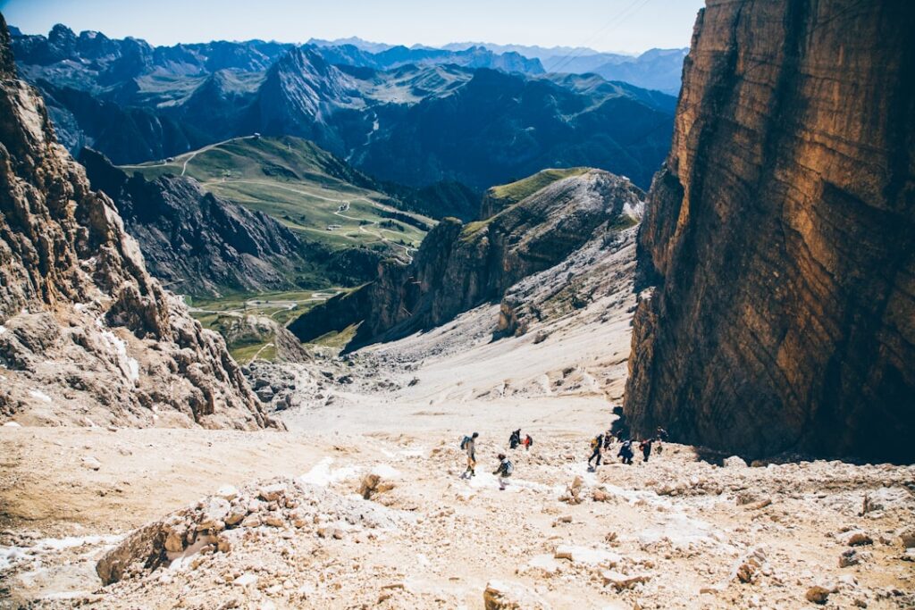 Gruppe Wanderer steigt über steinigen Schutt, steile Dolomitenwände und Talblick
