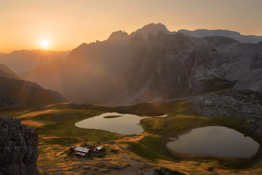Lever de soleil sur lacs alpins et refuge isolé dans les Dolomites