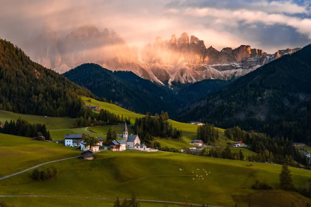 Village alpin avec église et montagnes éclairées au coucher, Dolomites