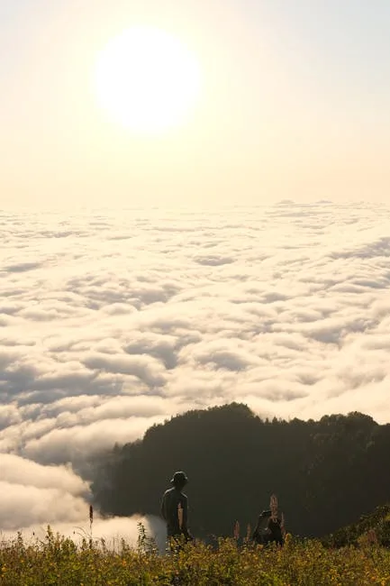 Deux randonneurs silhouettes observant une mer de nuages dans les Dolomites