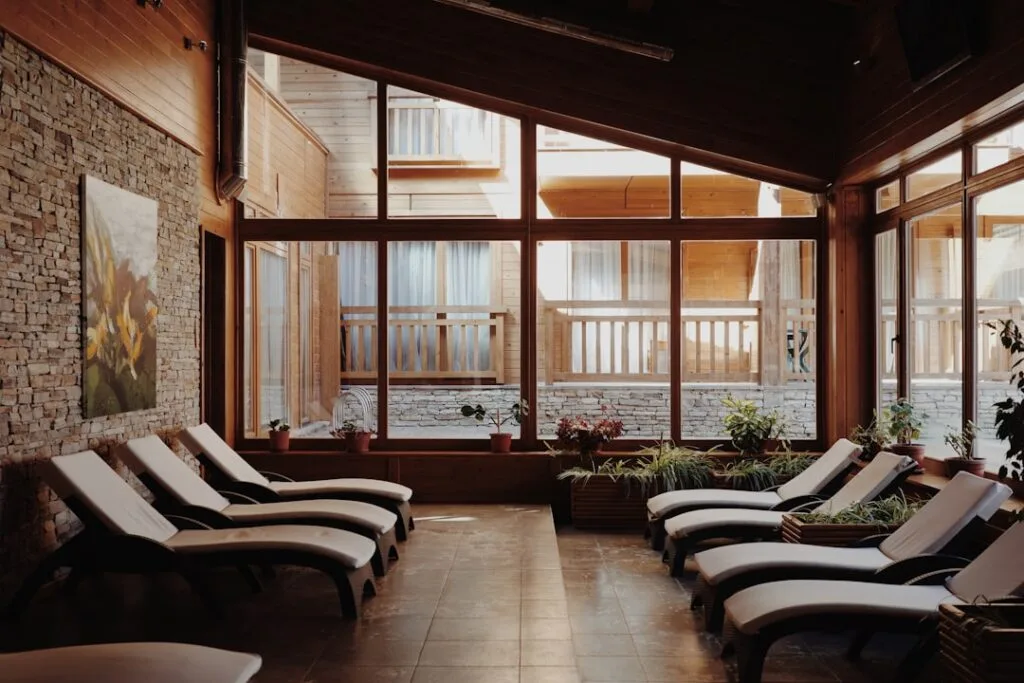 Salle de repos en bois avec transats et grandes fenêtres, spa Dolomites