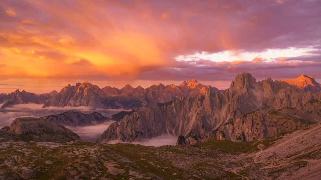 Gloeiende zonsondergang verlicht ruige pieken van de Dolomieten en wolken