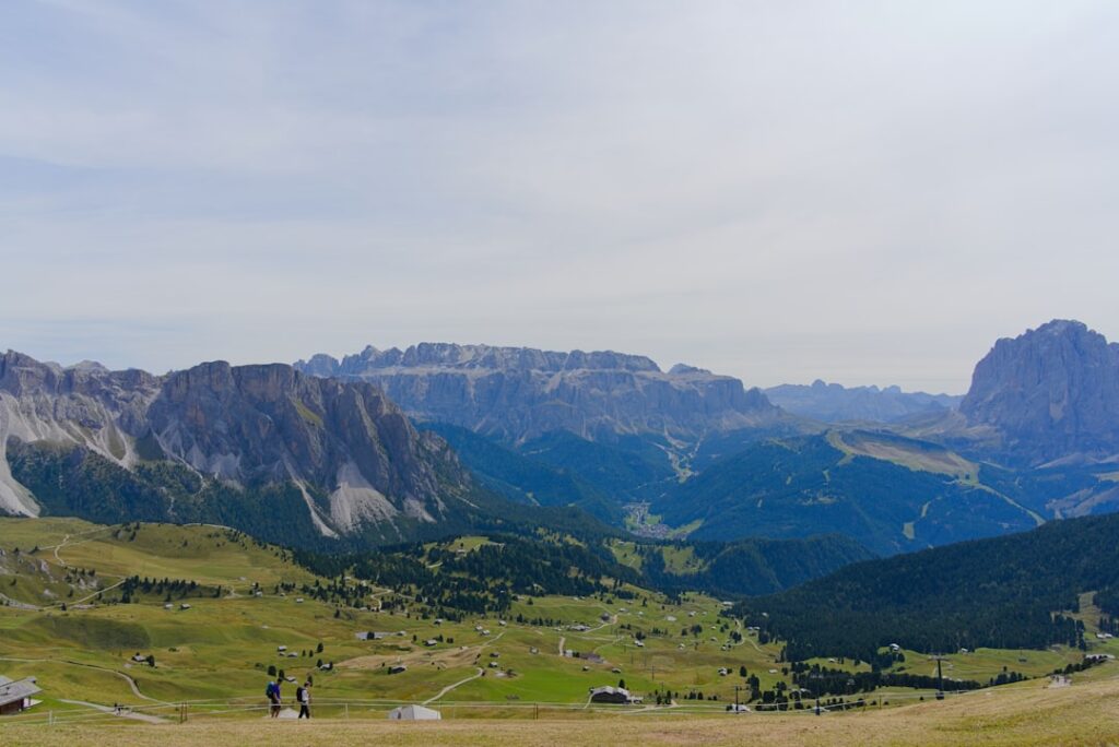 Weite Almwiesen und Wanderer mit weitem Blick auf die Dolomitenberge