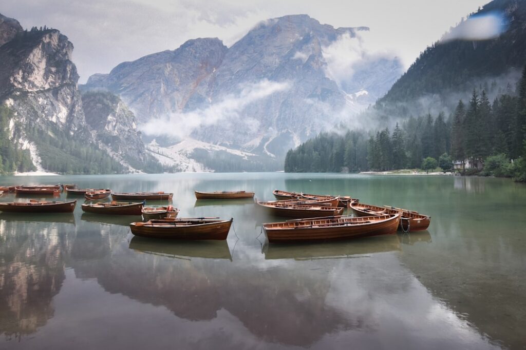 Rowboats moored on a misty Dolomites lake beneath rugged peaks
