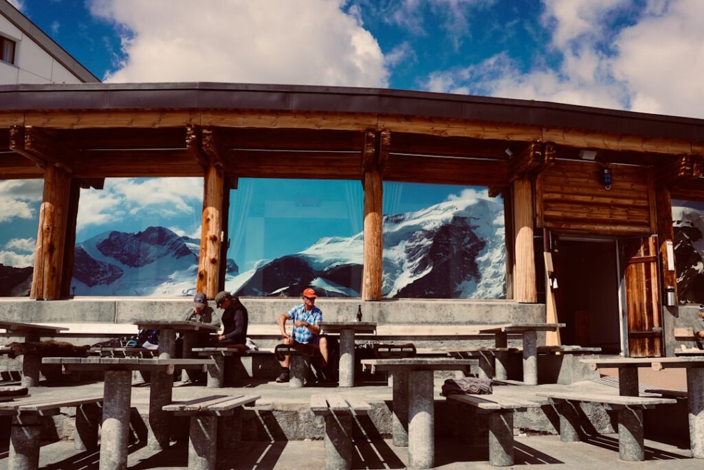 Bergterrasse mit Holzhütte und Fensterspiegelung der schneebedeckten Dolomiten