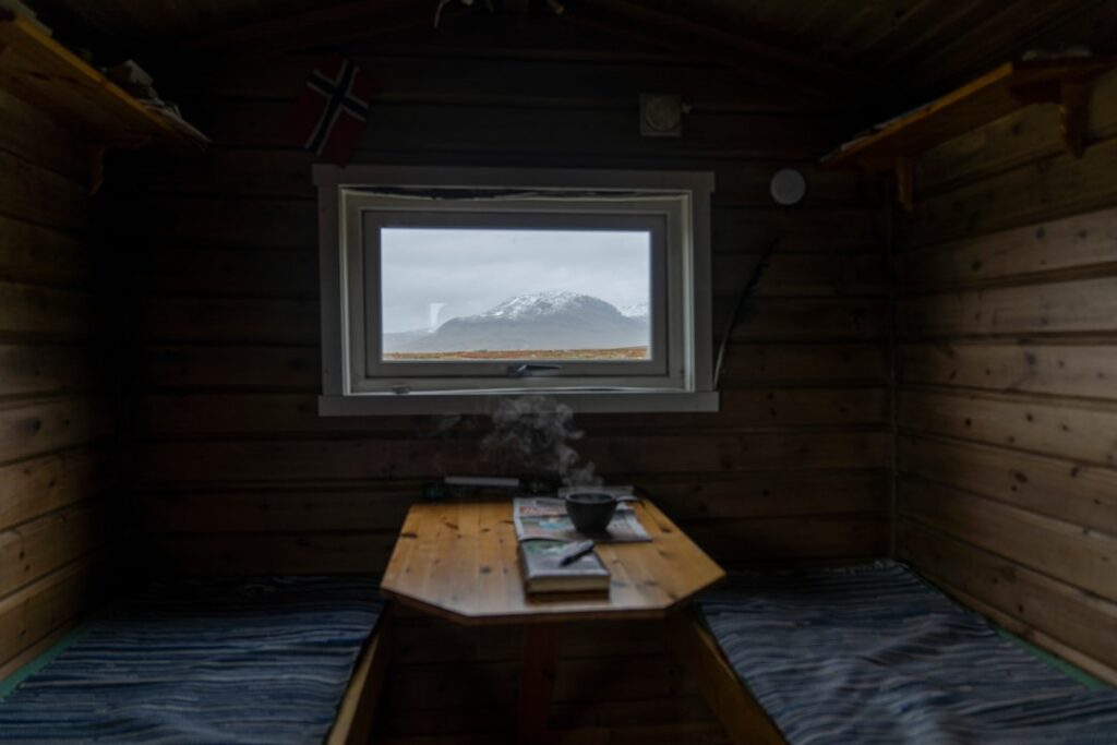 Cozy wooden rifugio interior with steaming cup and Dolomites view
