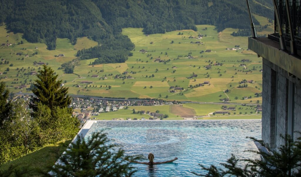 Allein schwimmende Person im Infinity-Pool mit weitem Blick auf Dolomiten