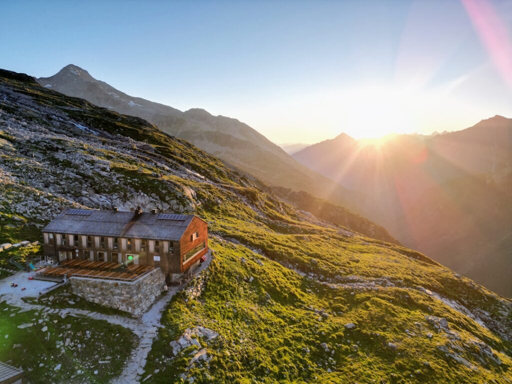 Wooden mountain hut on grassy Dolomites slope at sunrise