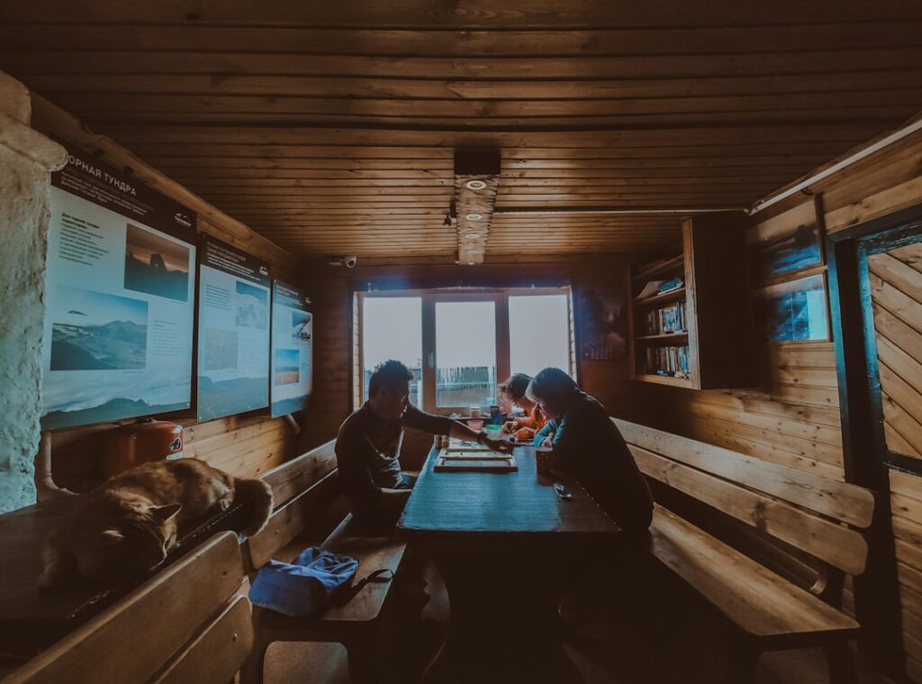 Wooden mountain hut interior in Dolomites with people sharing a meal