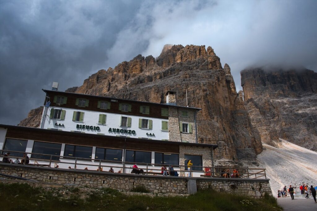 Refugio Auronzo chalet beneath towering Dolomites cliffs and storm clouds