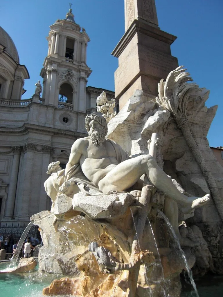 Gros plan d'une statue baroque du bassin, obélisque et église à Rome