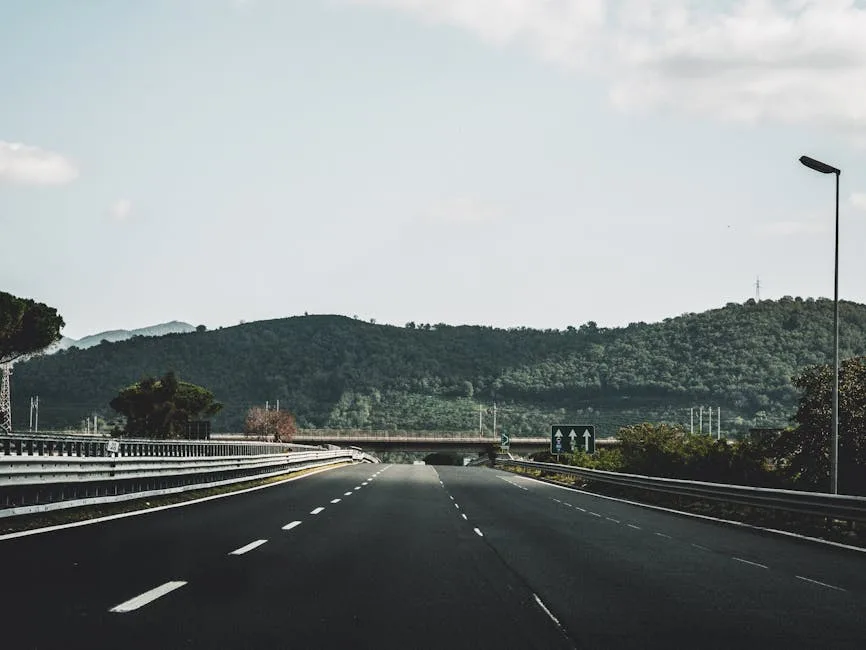 Autoroute dégagée traversant un paysage de collines boisées.