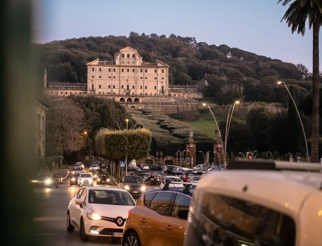 Trafic dense au crépuscule, palais et collines en arrière-plan à Rome.