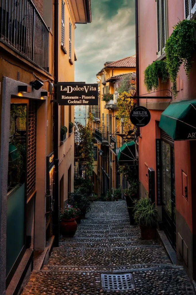 Ruelle pavée romaine bordée de boutiques, enseigne 'La Dolce Vita' visible
