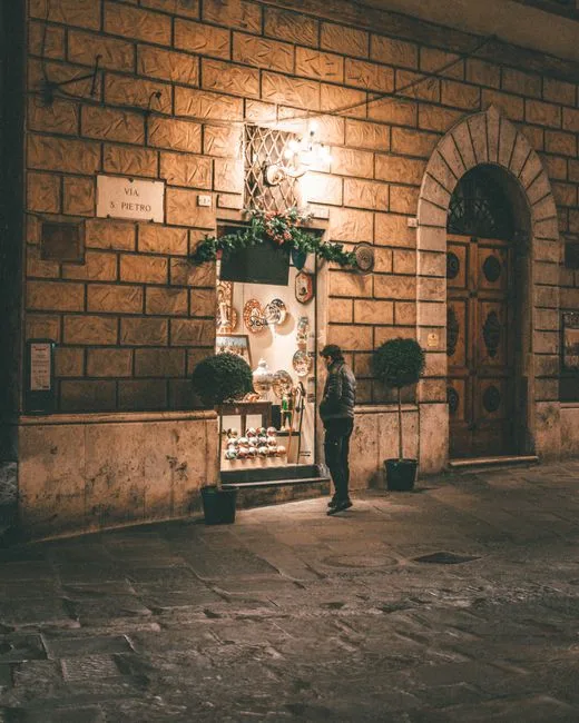 Boutique illuminée la nuit à Rome, client regardant des céramiques