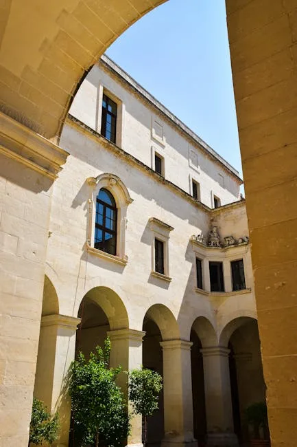Sunlit cloister courtyard with arches and small trees in Lecce