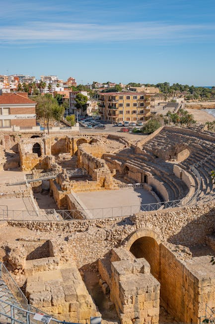 Remains of a Roman amphitheatre near the shoreline, houses in the background
