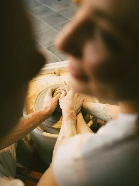 Couple shaping clay together in a pottery class
