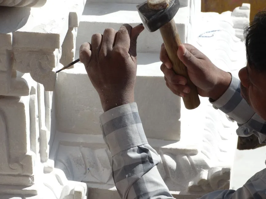 Hands carving pietra leccese in an artisan workshop