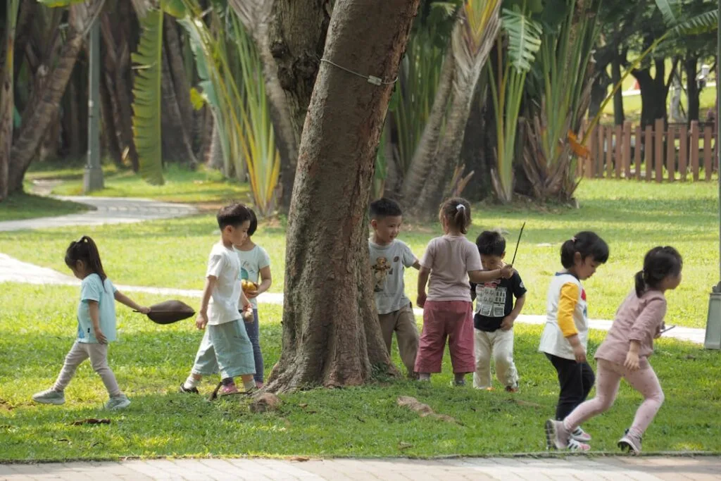 Public garden playground with children running under shady trees