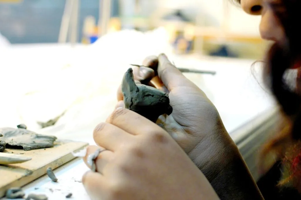 Child's hands shaping clay bird during a pottery workshop in Lecce