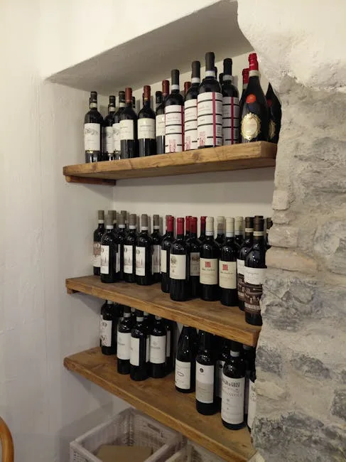 Étagères remplies de bouteilles de vin dans une trattoria turinoise, mur en pierre