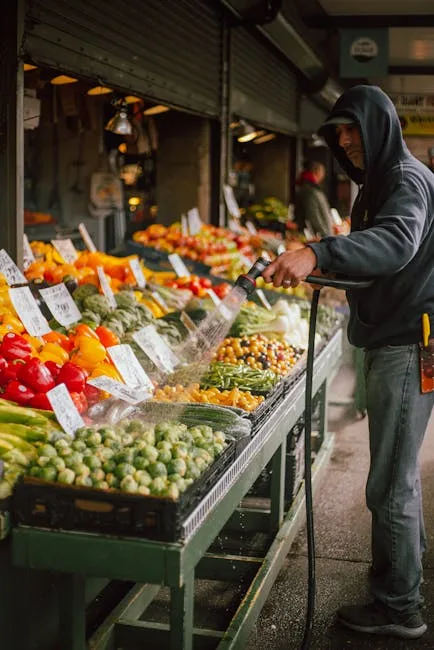 Vendeur arrosant étal de légumes colorés dans un marché