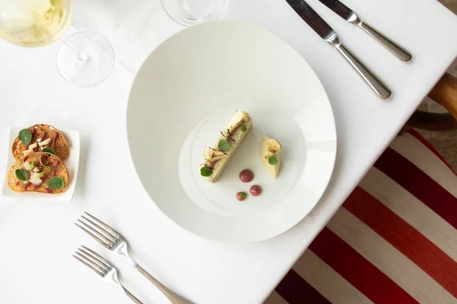 Assiette minimaliste servie sur nappe blanche dans un restaurant étoilé turinois