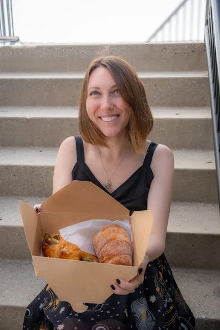 Femme souriante tenant une boîte de viennoiseries, assise sur des marches à Turin