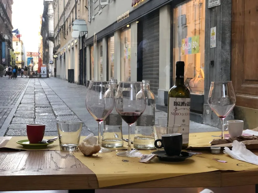 Verres de vin et tasses sur une table en terrasse, rue piétonne de Turin