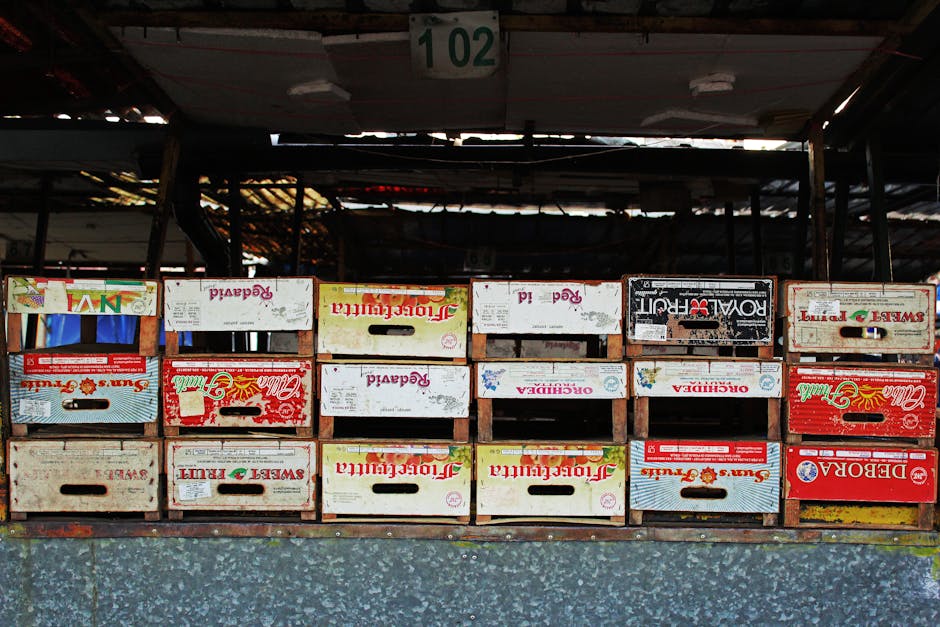 Rangée de caisses en bois colorées empilées sous un hangar de marché