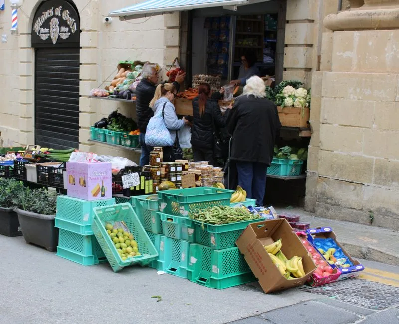 Petit étal de quartier avec cagettes vertes et clients à Turin
