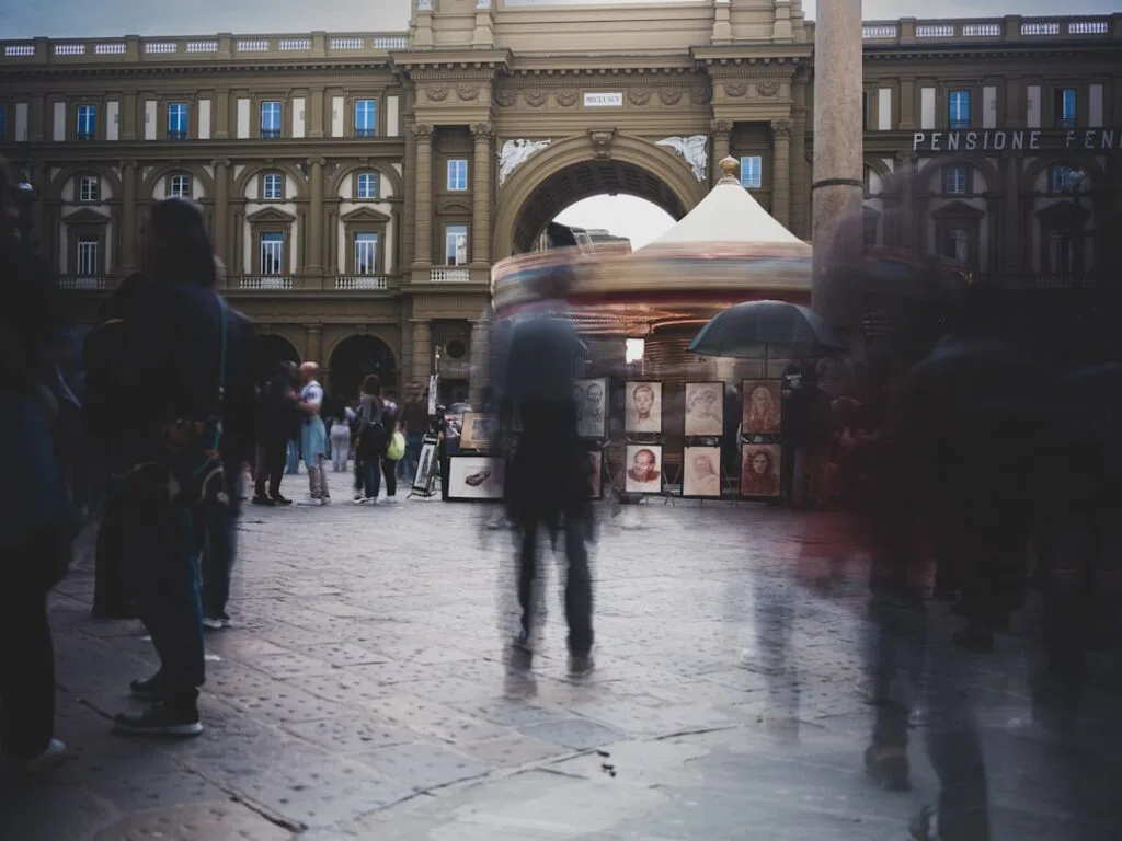 place animée près d'un carrousel flou, passants flous devant arcade à Turin