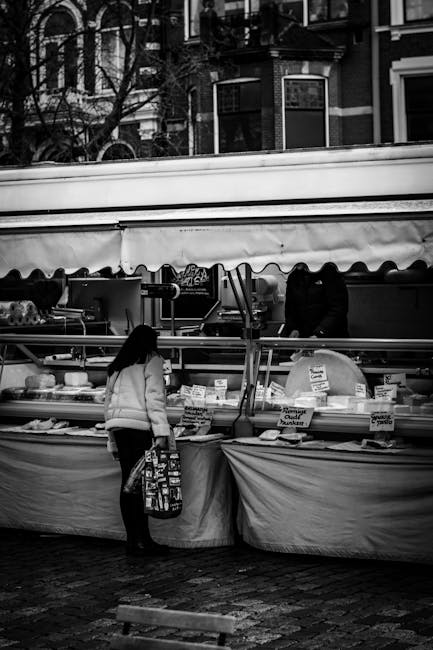 cliente regardant étal de fromages sous tente au marché, noir et blanc, à Turin