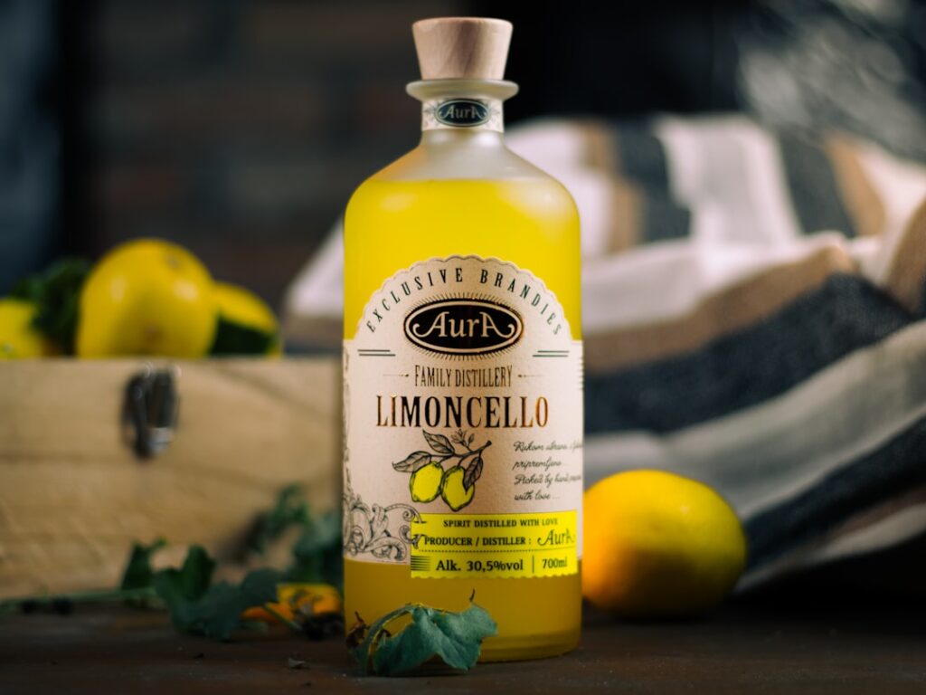 Fles limoncello op tafel met citroenen, Côte amalfitaine op de achtergrond