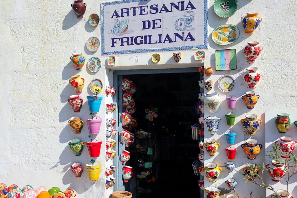 Kleurrijke keramieken potten rondom deur met 'Artesania de Frigiliana'