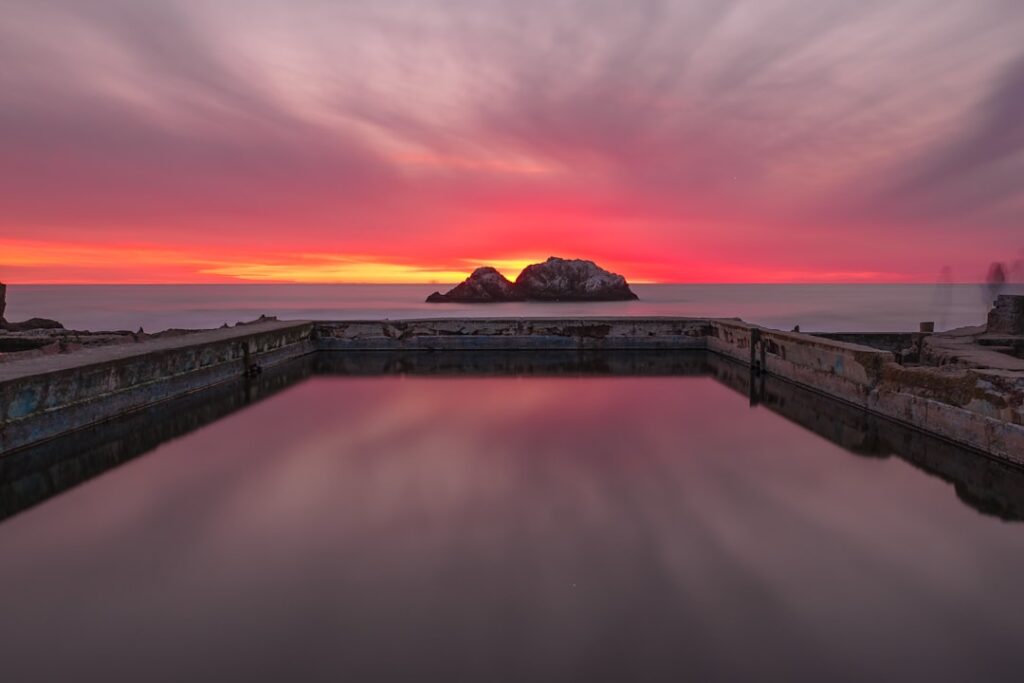 Rustige waterreflectie en felgekleurde zonsondergang boven de open zee