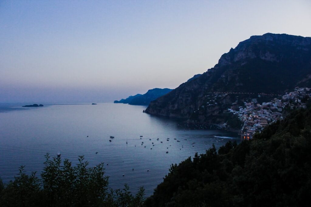 Dämmernde Küstenlinie und Boote vor Positano in der Côte amalfitaine