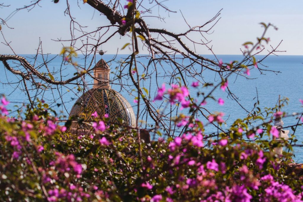 Gemusterte Kuppel der Kirche hinter Bougainvillea mit Meerblick, Côte amalfitaine
