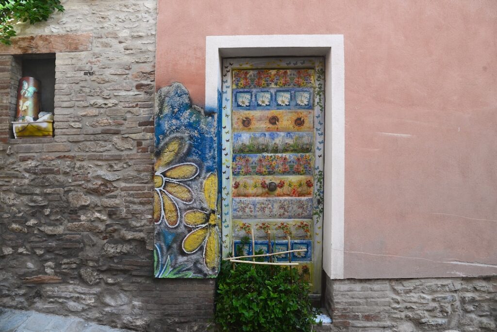Narrow painted wooden door with floral panels set into Amalfi Coast wall