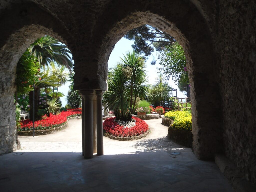 Arcades en pierre encadrant un jardin fleuri au sommet de la Côte amalfitaine