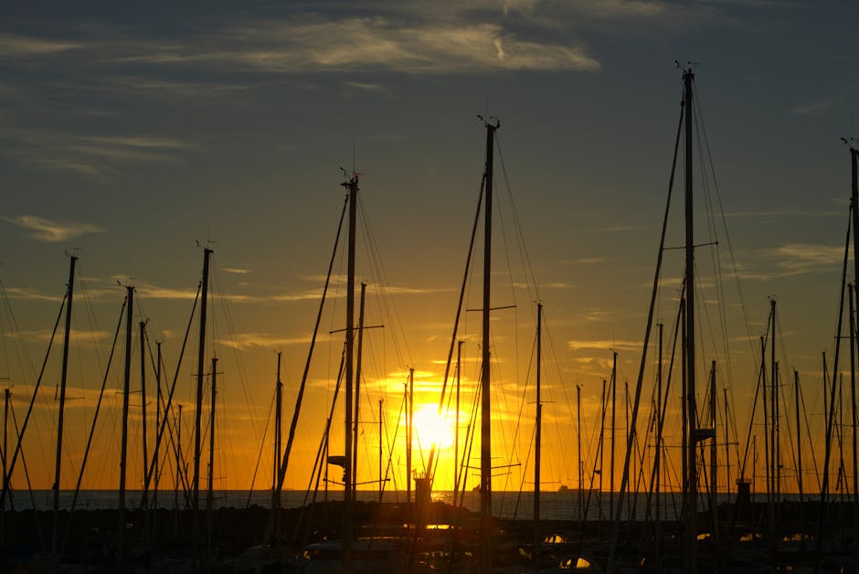 Tall sailboat masts silhouetted at golden sunrise over Côte amalfitaine marina