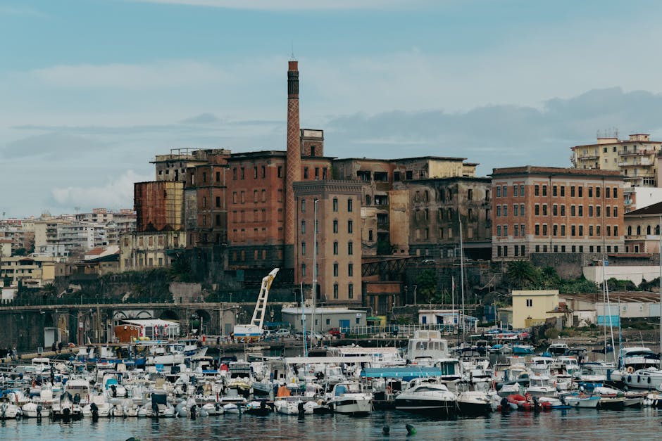 Porto affollato di barche davanti a edificio industriale sulla Costiera Amalfitana