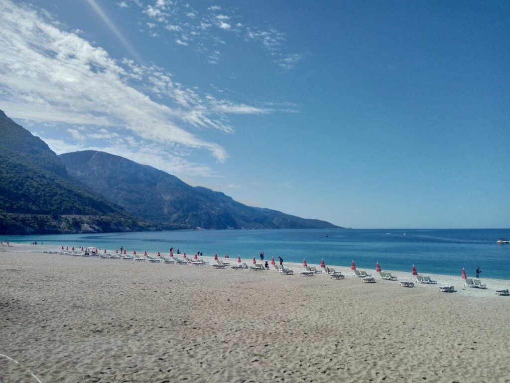 Empty rows of sunbeds and red umbrellas on a broad Amalfi Coast beach