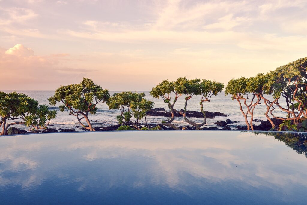 Piscine à débordement réfléchissant le ciel, arbres et mer de la Côte amalfitaine