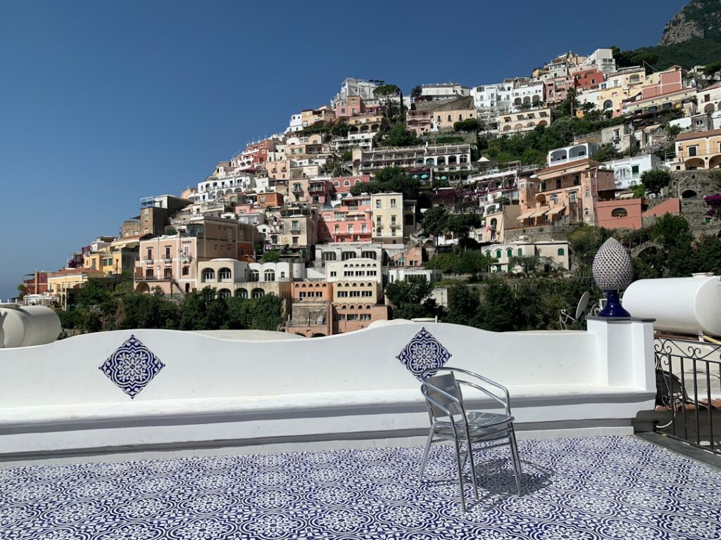 Terrassentisch und Stuhl vor bunten Häusern an der Côte amalfitaine.